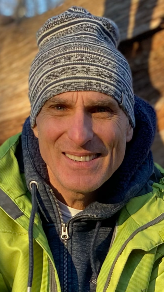 Perry Hartwick headshot. He is wearing a grey toque and green jacket smiling at the camera.