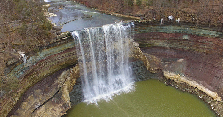 Aerial photo of Twenty Mile Waterfall with exposed rock units in a semicircular shape behind the falls.