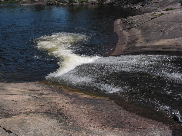 Smooth rocks with a small amount of water flowing down them making a natural waterslide