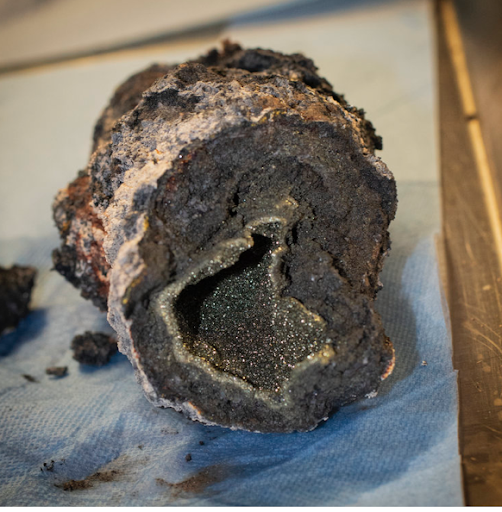 A black rock with a hollow inside sits on a paper on a table