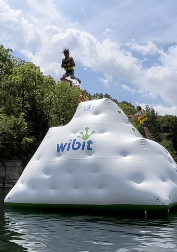 A kid in mid-air jumping off a large inflatable tower shaped like an iceberg.