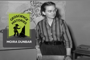 A black and white photograph of a young woman in a striped shirt with glasses. She is standing in front of a desk and there is a map of Canada on the wall behind her. On top of the photo text reads: "Geoscience Histories. Moira Dunbar."
