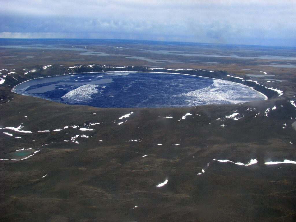 An aerial shot of a massive crater filled with water and ice.