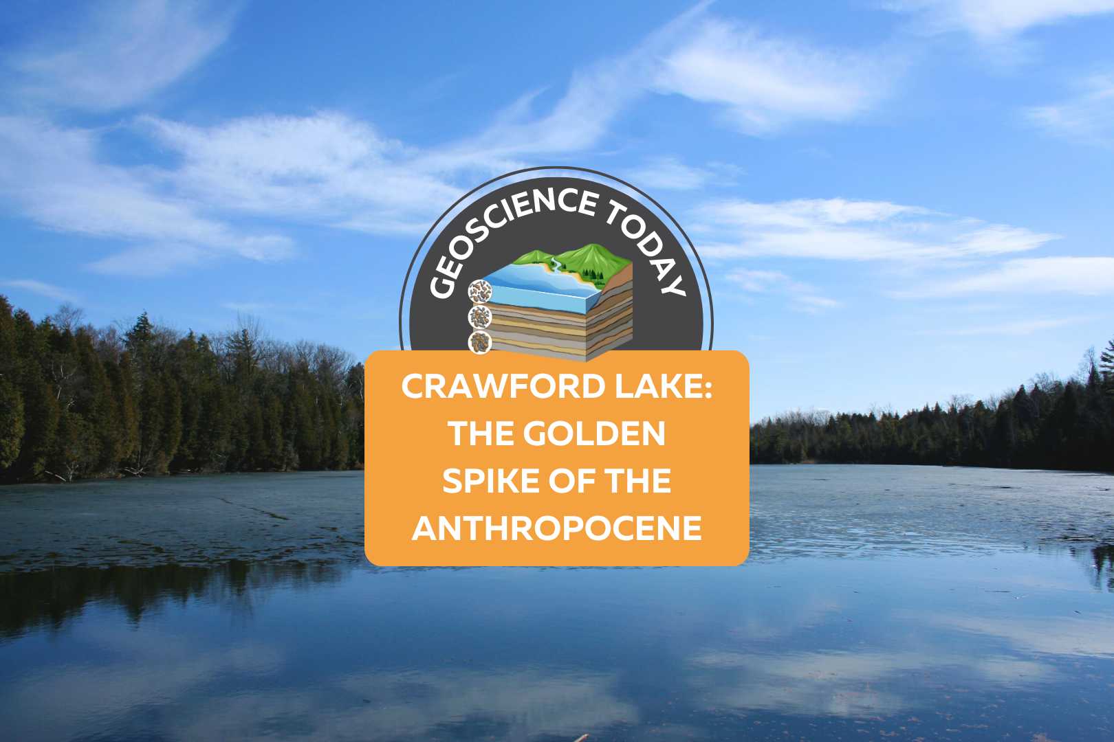 A still, flat lake with evergreen trees on the opposite shore and a blue sky above. On top of the photo text reads: Geoscience Today. Crawford Lake: The Golden Spike of the Anthropocene.
